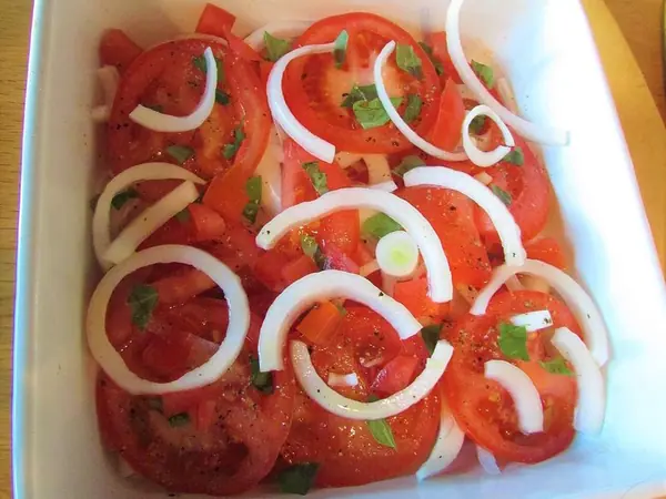 Sallatë me domate dhe borzilok e servirur në tryezë