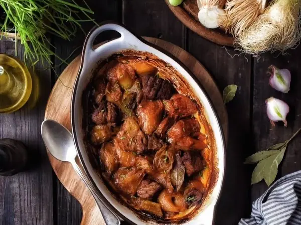 Tavë qengji me fasule e servirur në tryezë